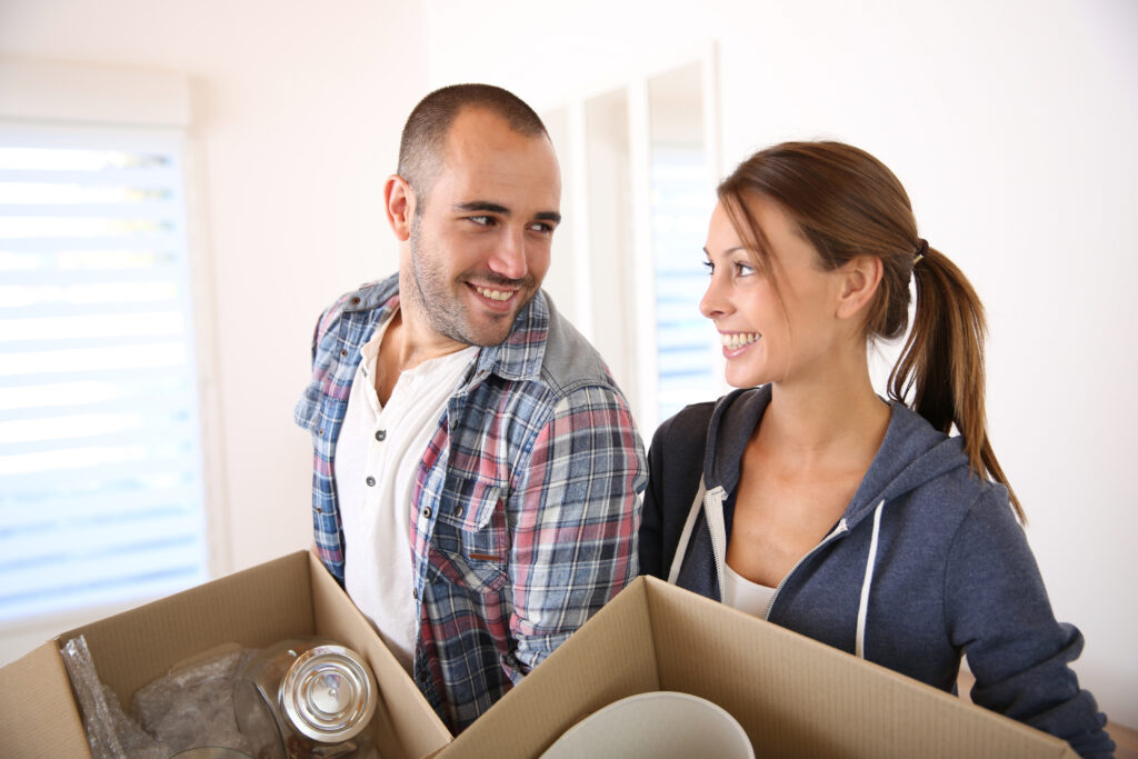 Cheerful young adults packing their stuff in cardboards