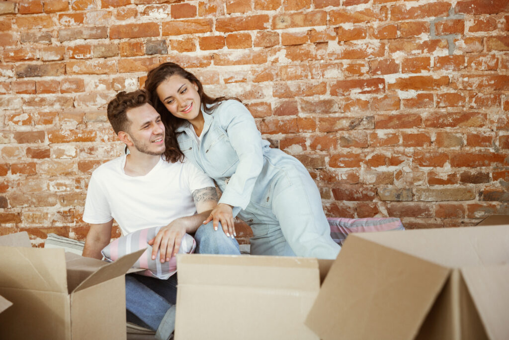 Young couple moved to a new house or apartment. Lying together, caddling, hugging, having fun at moved day.