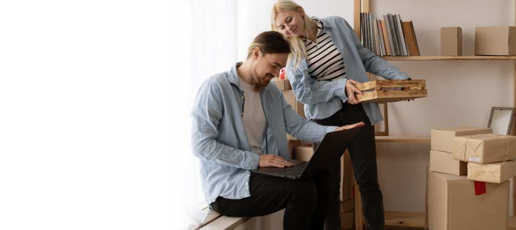 Young couple moving to a new home relaxing sitting using computer laptop, smiling happy for moving to new apartment.