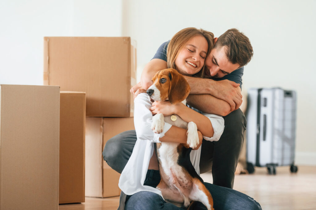 Embracing each other. Young couple with dog are moving to new home.