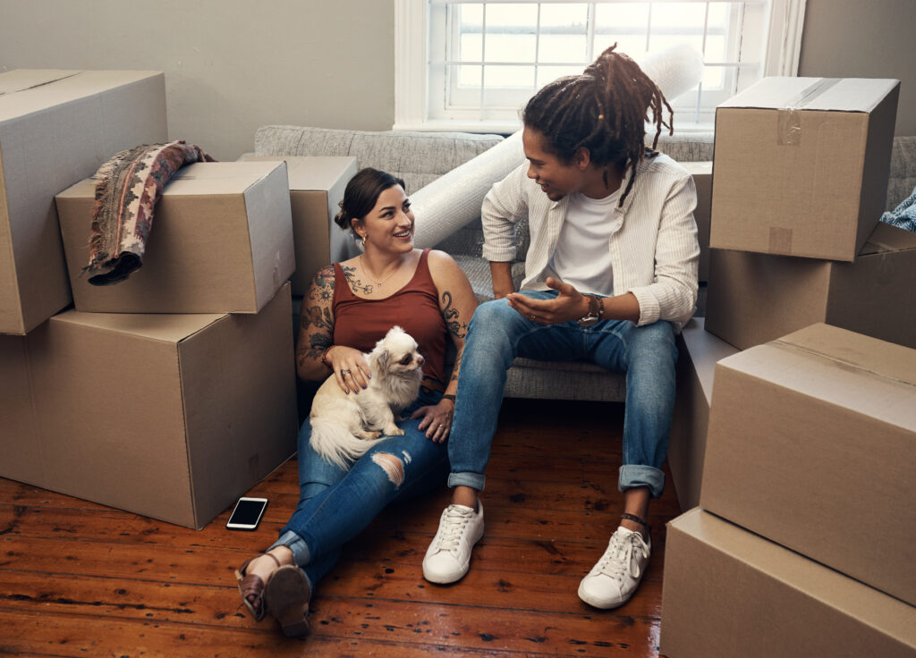 Shot of a couple sitting with their dog while taking a break on moving day.